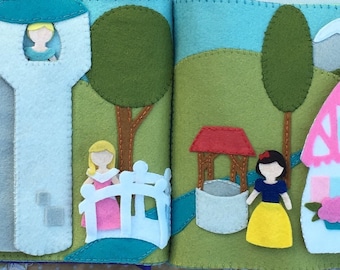 May include: A felt book with two pages depicting a princess in a tower, a princess crossing a bridge, a well, and a cottage. The pages are made of felt and have a stitched border.