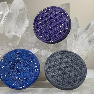 May include: Three round, decorative coasters with a geometric pattern. The coasters are made of a dark blue, light blue, and gray material with a glittery finish.