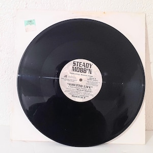 May include: Black vinyl record with a white label. The label has the text "STEADY MOBB'N" featuring Snap Dogg. The title of the song is "GHETTO LIFE" by Black Mafia. The record is produced by Master P.