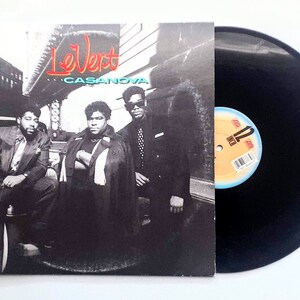 May include: A black and white photo of three people standing in front of a car. The album cover features the text "LeVert CASANOVA" in green and blue lettering.