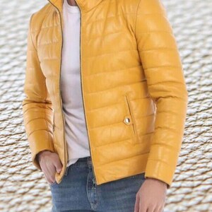 May include: A yellow quilted leather jacket with a zipper closure. The jacket has a stand-up collar and a pocket on the left side.