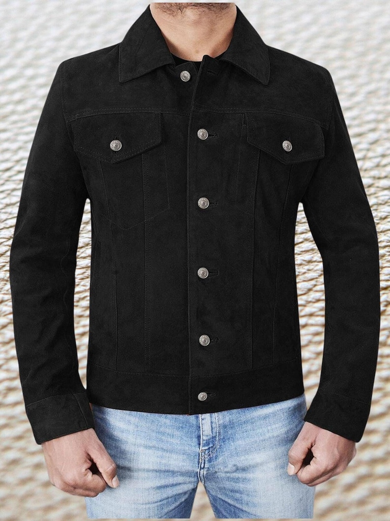 May include: A black suede jacket with a classic denim jacket style. It has a button-up front, two chest pockets, and long sleeves.