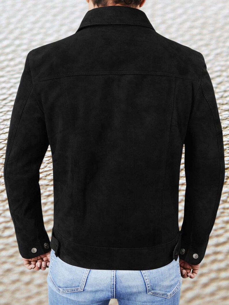 May include: A black suede jacket with a collared neckline and long sleeves. The jacket has a button closure and two pockets on the front.