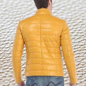 May include: A yellow quilted leather jacket with a zipper closure. The jacket has a stand-up collar and long sleeves.