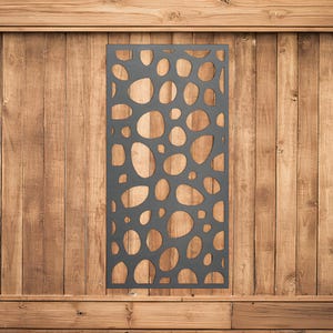 May include: A black metal screen with a cut-out design of overlapping circles and ovals. The screen is mounted on a wooden wall.