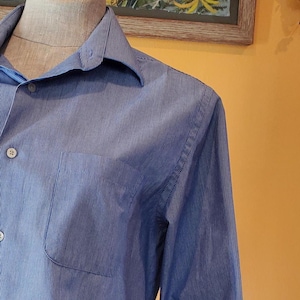 May include: A blue striped long-sleeve button-down shirt with a pocket on the left side.