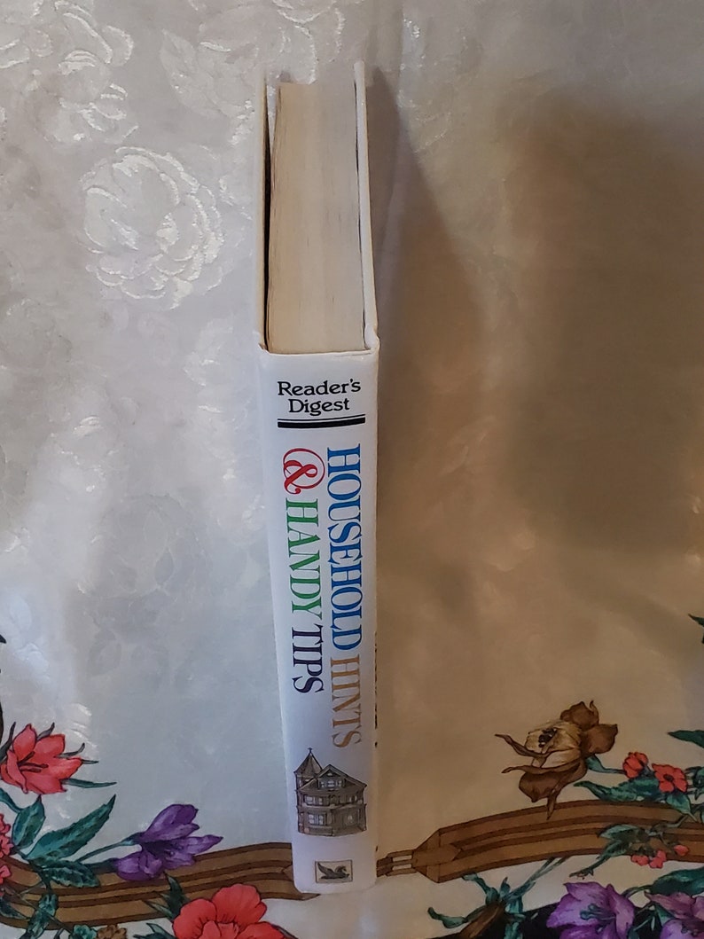 May include: A white book with blue, green, and red text that reads "Household Hints & Handy Tips" and "Reader's Digest". The book has a picture of a house on the cover.