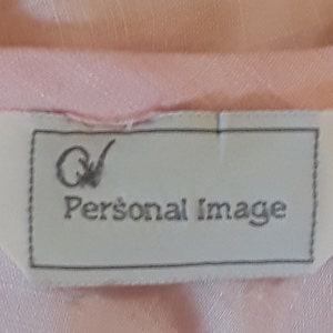 Op de afbeelding: Een wit label met een zwarte rand en de tekst "QV Personal Image" in zwarte letters.