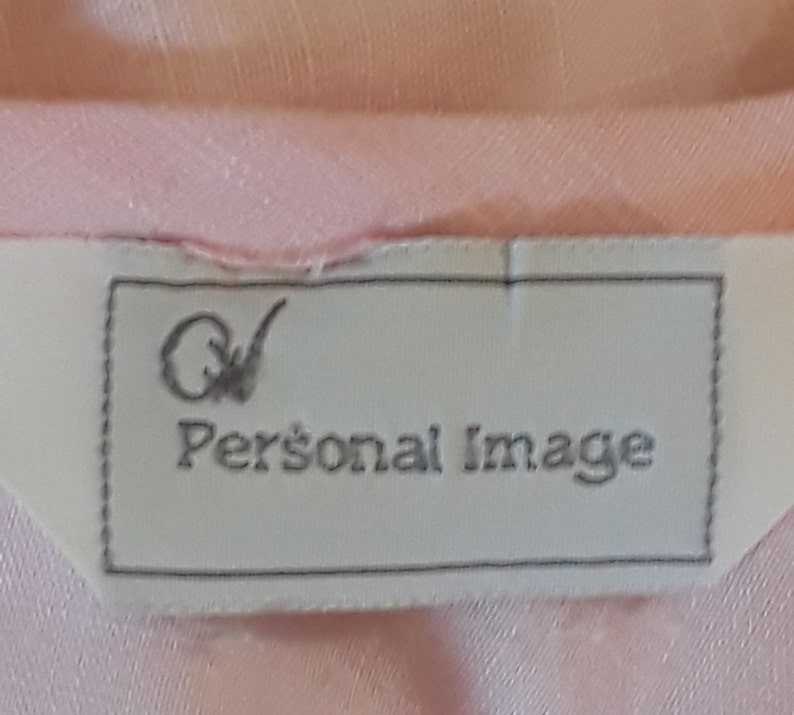 Op de afbeelding: Een wit label met een zwarte rand en de tekst "QV Personal Image" in zwarte letters.