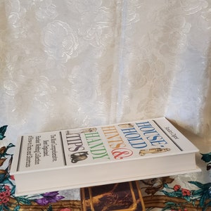 May include: A white book titled "House Hold Hints & Handy Tips" with the text "The Most Comprehensive, Best Organized, Hardest Working Collection of How-to Facts and Shortcuts" on the cover.