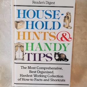 May include: A white book with a colourful title that reads "HOUSEHOLD HINTS & HANDY TIPS". The book is published by Reader's Digest and features the text "The Most Comprehensive, Best Organized, Hardest Working Collection of How-to Facts and Shortcuts".