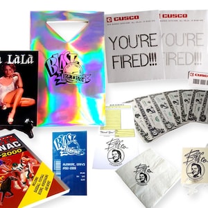 以下が含まれることがあります： 「Oh Là Là」の文字が入った雑誌、ホログラフィックショッピングバッグ、「You're Fired!!!」と書かれた紙、おもちゃのお金、そして「Biff Tannen Museum」のチケットなど、小道具や記念品のコレクション。