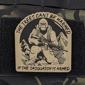 May include: A brown patch with a black and white illustration of a sasquatch holding a rifle. The text reads "The trees can't be harmed if the sasquatch is armed."