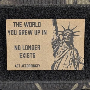 May include: A brown patch with the text "THE WORLD YOU GREW UP IN NO LONGER EXISTS ACT ACCORDINGLY" and a black and white image of the Statue of Liberty with a skull.