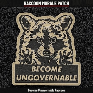 May include: A tan and black morale patch featuring a detailed illustration of a raccoon with its paws raised. Below the raccoon, a rectangular black banner displays the text BECOME UNGOVERNABLE in bold, tan, capitalized lettering.