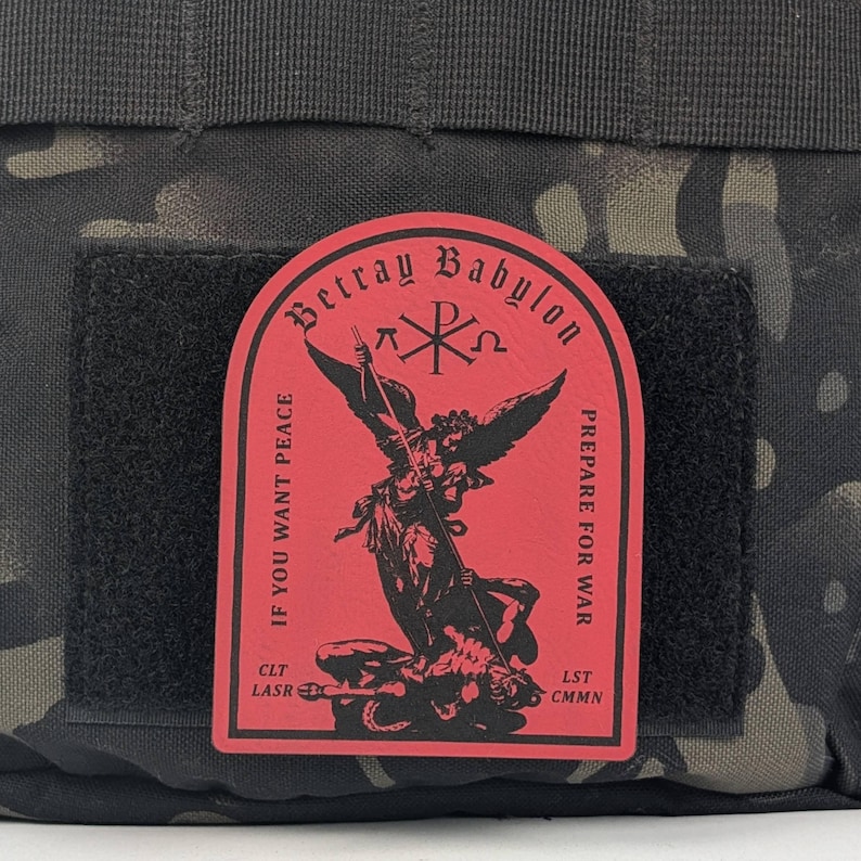 May include: Red patch with black text and an image of an angel defeating a demon. The text reads "Betray Babylon", "Prepare for War", "If you want peace", "CLT LASR", and "LST CMNN".