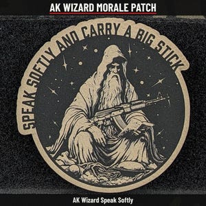 May include: A circular morale patch featuring a tan-colored illustration of a hooded wizard with a long beard holding a rifle and a book. The text reads SPEAK SOFTLY AND CARRY A BIG STICK, set against a black background with stars.