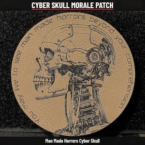 May include: A circular tan morale patch featuring a black line-art illustration of a robotic skull with exposed mechanical components and wiring. The text "You may live to see man made horrors beyond your comprehension" is printed in a circular arc.