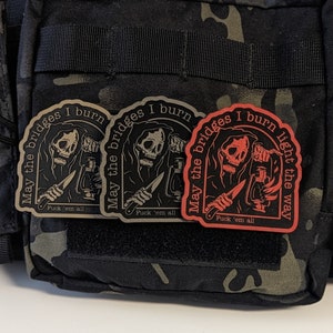 May include: Three patches with a grim reaper design. The patches are black, tan, and red, with the text "May the bridges I burn" and "Fuck 'em all". The red patch also says "light the way".
