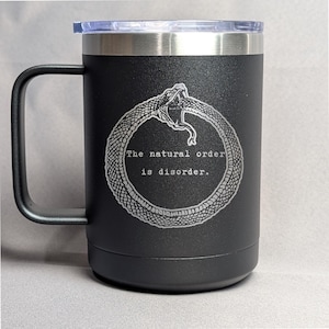 May include: Black stainless steel travel mug with a black snake wrapped around a circle and the text "The natural order is disorder."