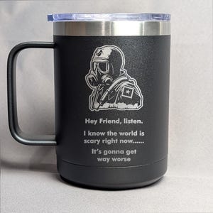 May include: Black stainless steel travel mug with a black and white graphic of a person wearing a gas mask and the text "Hey Friend, listen. I know the world is scary right now...... It's gonna get way worse".