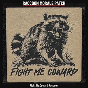 May include: A square morale patch featuring a tan background with a black graphic of a snarling raccoon. The text RACCOON MORALE PATCH appears at the top, and the text FIGHT ME COWARD is printed in black at the bottom of the patch.