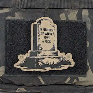 May include: A black and white illustration of a tombstone with the text "In memory of when I gave a fuck". The tombstone is surrounded by grass and flowers.
