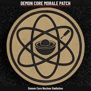 May include: A circular tan morale patch featuring a black atomic symbol graphic with a central sphere and a screwdriver icon. The text DEMON CORE MORALE PATCH appears at the top, and Demon Core Nuclear Radiation is at the bottom.