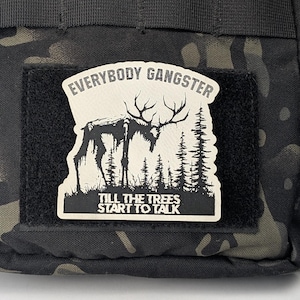 May include: A white patch with black text and a black and white illustration of a deer in a forest. The text reads "Everybody Gangster Till The Trees Start To Talk."