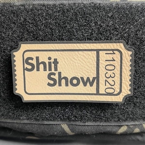 May include: A tan-colored ticket with black text that reads "Shit Show" and "110320".