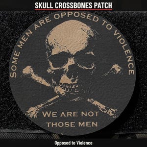 May include: A circular black patch featuring a tan skull and crossbones graphic. The text reads: SOME MEN ARE OPPOSED TO VIOLENCE WE ARE NOT THOSE MEN. The patch has a textured surface and is set against a dark, fuzzy background.