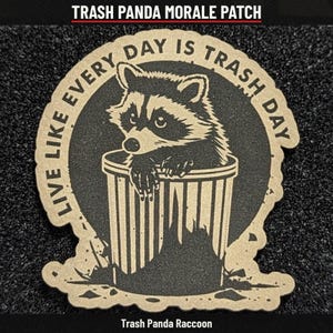May include: A tan and black morale patch featuring a raccoon peeking out of a trash can. The circular design includes the text "LIVE LIKE EVERY DAY IS TRASH DAY" arched around the raccoon. The patch has a die-cut edge and a textured finish.