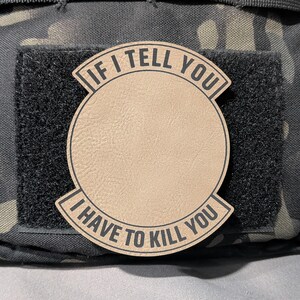 May include: A tan patch with the text "IF I TELL YOU I HAVE TO KILL YOU" in black, arched around a central circle. The patch is attached to a black velcro square, set against a camouflage background.