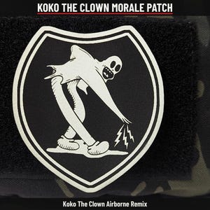 May include: A black and white morale patch featuring a shield shape with a graphic of a cartoon clown figure reaching down to create lightning bolts. The text KOKO THE CLOWN MORALE PATCH and Koko The Clown Airborne Remix is visible.