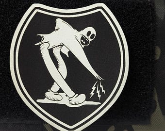 May include: A black and white morale patch featuring a shield shape with a graphic of a cartoon clown figure reaching down to create lightning bolts. The text KOKO THE CLOWN MORALE PATCH and Koko The Clown Airborne Remix is visible.