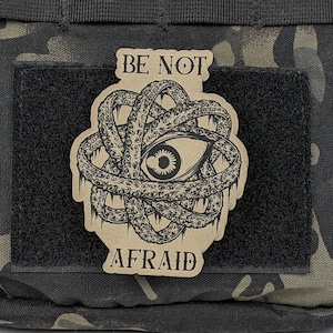 May include: A brown patch with a black and white illustration of an eye surrounded by tentacles. The text "BE NOT AFRAID" is printed on the patch.