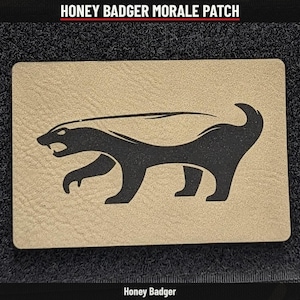 May include: A rectangular morale patch featuring a tan textured background with a black silhouette of a honey badger in profile. The badger is depicted in a walking stance with its mouth open, showing teeth. The text HONEY BADGER MORALE PATCH is visible.