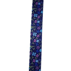 May include: A close-up of a dark blue ribbon with a floral pattern in shades of pink, blue, and green.