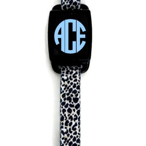 May include: A black and white leopard print strap with a black buckle and a round black button with the letters "ACE" in light blue.