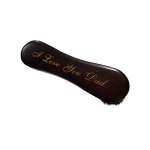 May include: A dark brown wooden brush with a black bristle brush head. The brush has the words "I Love You Dad" engraved in gold lettering.