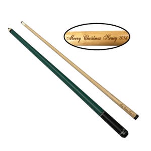 May include: A green and black pool cue with a wooden shaft. The shaft is engraved with the text "Merry Christmas Honey 2013".