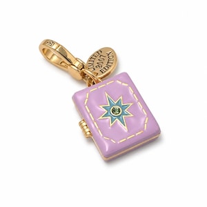 May include: A gold-tone metal charm shaped like a rectangular book with lavender enamel, featuring a central blue star design with a small green crystal. A small oval tag attached to the lobster clasp is engraved with the text LIMITED 2007 EDITION.
