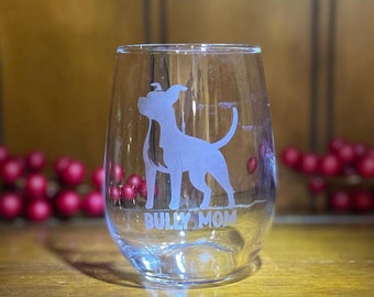 May include: A clear glass wine glass with an etched design of a dog and the text "Bully Mom".