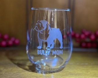 May include: A clear glass wine glass with an etched design of a bulldog and the text "Bully Mom".