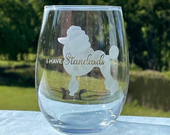 May include: A clear glass wine glass with a white silhouette of a poodle and the text "I have Standards" etched on the side.