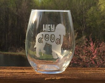 May include: A clear glass wine glass with the text "Hey dood" and a silhouette of a doodle dog etched on the side.