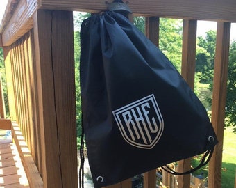 May include: Black drawstring bag with a white embroidered shield logo that says "RHE" on it.