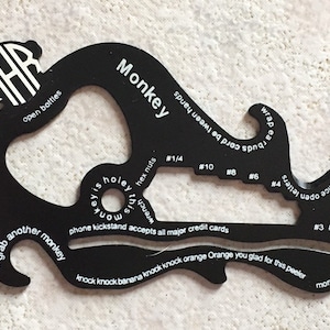 May include: A black multi-tool with the word "Monkey" printed on it. The tool has a variety of functions, including a bottle opener, a phone kickstand, a ruler, and a hex nut wrench. It also has the text "knock knock banana knock knock orange Orange you glad for this peeler" printed on it.