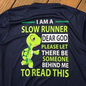 Puede incluir: Una camiseta azul marino con un gr&aacute;fico de tortuga verde y el texto "Soy un corredor lento. Dios m&iacute;o, por favor, que haya alguien detr&aacute;s de m&iacute; para leer esto."