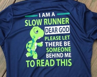 May include: Navy blue athletic shirt with the text "I AM A SLOW RUNNER DEAR GOD PLEASE LET THERE BE SOMEONE BEHIND ME TO READ THIS" and a cartoon turtle graphic in green and white.